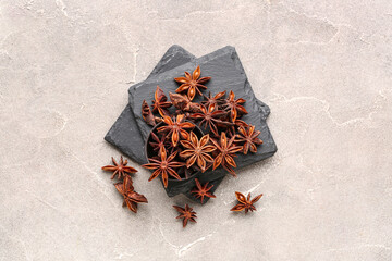Slate boards with bowl of aromatic star anise on grunge background