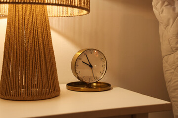Alarm clock with glowing lamp on table in bedroom at night, closeup