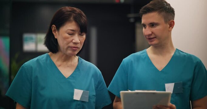 Walking, teamwork and nurses with clipboard for healthcare, checklist and medical information while talking. Hospital, surgeon and intern with document for diagnosis, review or filling forms in Japan