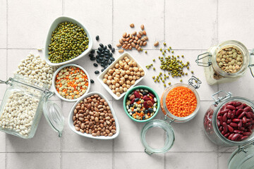 Composition with different raw legumes on light tile background
