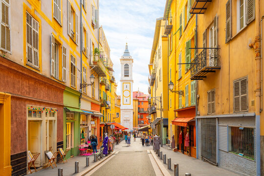Fototapeta View of the campanile bell tower of the Nice Cathedral at Place Rossetti as tourists enjoy the narrow streets in the colorful Vieux Ville old town of Nice, France.