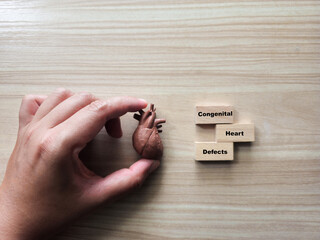 A miniature heart is placed beside three wooden blocks spelling 