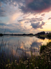 Calm river at sunset with reflective sky in rural countryside landscape
