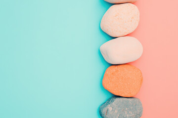 Obraz premium Emotional Balance. A line of colorful stones on a split pastel background of blue and pink, showcasing natural textures and soothing colors.
