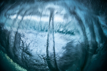 An abstract underwater view capturing the dynamic energy and swirling motion of breaking waves in...