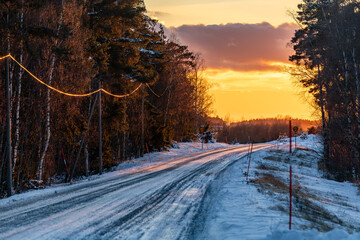 Stockholm, Sweden An icy and forested road in a winter sunset.