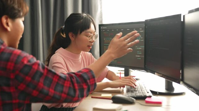 Slow motion back end software developer engineer for computer programming working together on debugging writing computing code, solving complex algorithms display on monitor in office. Burgeoning