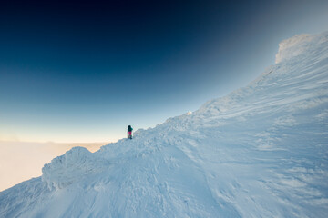 Climber in the mountains. A girl walks through the snow in the mountains.