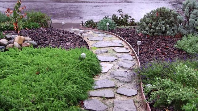 Rain Falling On Pathway To Sidewalk And Street Through Landscaped Yard
