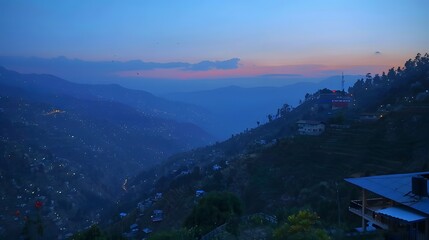 Obraz premium Twilight view of mountain village with lights and hazy valley.