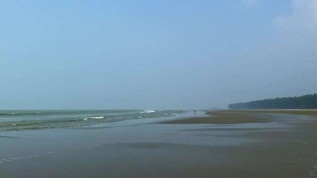 A breathtaking view of the sun setting over the horizon at Cox's Bazar, the world's longest natural sea beach, with waves crashing gently on the shore.