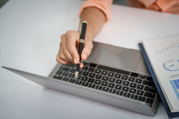 A close-up of a businesswoman working on a laptop in an office. As an accountant, she records...