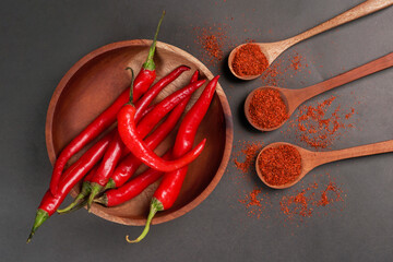 Large red chili and chilli powder served on wooden bowk isolated on a black background