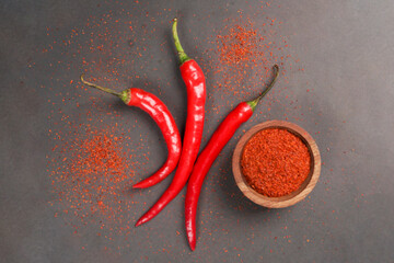 Large red chili and chilli powder served on wooden bowk isolated on a black background
