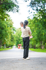 A mother carries her little daughter through a green space surrounded by trees. They enjoy fresh air, outdoor fun, and quality time together, embracing nature on a beautiful sunny day