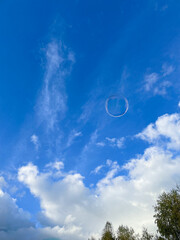 Soap bubble against the background of a cloudy blue sky. Vertical photo