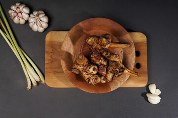 Top of view fresh galangal root on wooden bowl isolated on black background. Ingredients of herbs for healing and healthy food or medical concept.