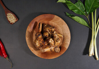 Top of view fresh galangal root on wooden bowl isolated on black background. Ingredients of herbs for healing and healthy food or medical concept.