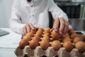A businessman checks eggs at a work table in a factory, ensuring cleanliness and freshness. Food...