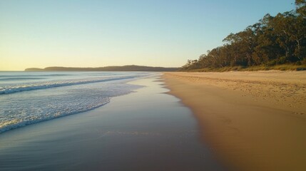 A quiet, serene beach at sunrise with soft morning light illuminating the coastline and wet sand