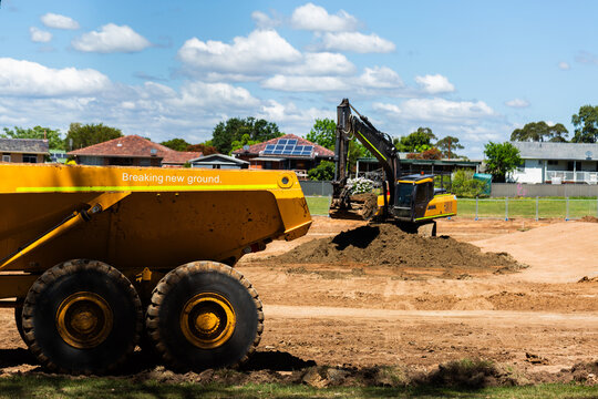dump truck and excavator on worksite moving dirt on bright sunlit day