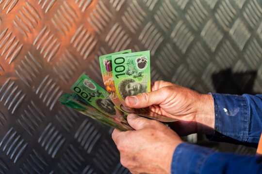 Middle aged man holding hundreds of dollars of Australian cash beside meal tool box on ute