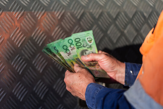 Middle aged man holding hundreds of dollars of Australian cash beside meal tool box on ute