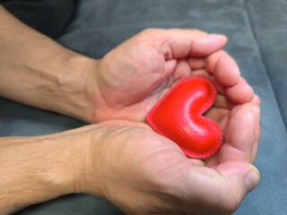 close-up of hands holding a red heart