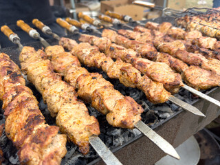 A bunch of meat skewers are being cooked on a grill