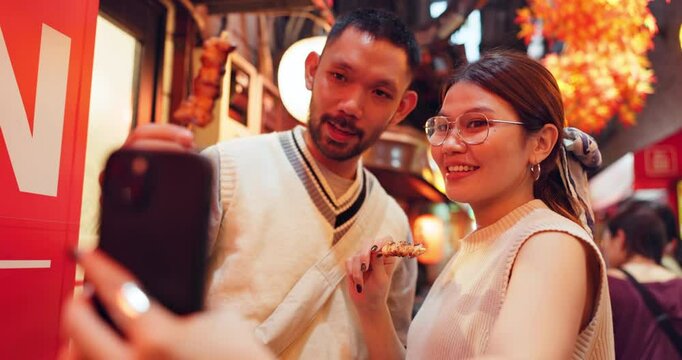 Asian couple, selfie and street food with skewers or kebabs for traditional or local cuisine in Japan. Japanese, man and woman with picture, photography or memory for omoide yokocho together in Tokyo