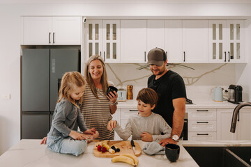 Parents teaching kids how to cut fruits in the kitchen.