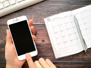 スマホを操作する手とスケジュール帳