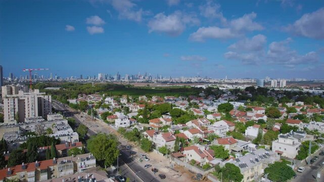 Panning shot above the city of Holon and the residential areas in its city center with the skyline of the city of Tel Aviv in the background