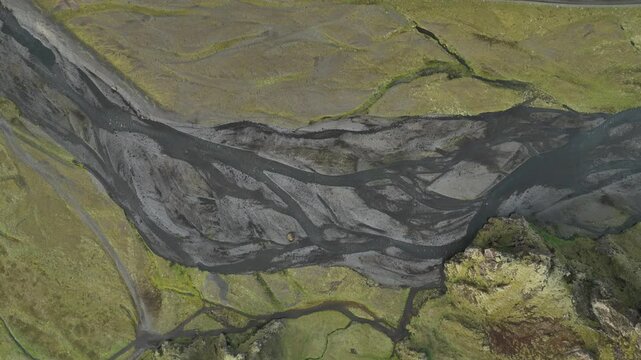 A stunning aerial view of Thakgil, Iceland, featuring intricate braided river formations flowing through volcanic terrain and lush mossy fields.