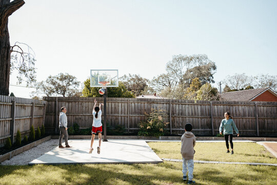 Family playing basketball in their yard.