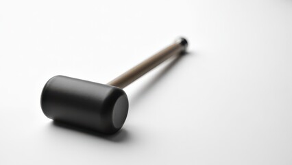 Rubber mallet for automotive work. Black rubber mallet with a wooden handle rests on a clean, white surface, casting a soft shadow to the left.