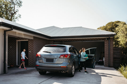 Middle-aged woman getting out of the car in the driveway of home