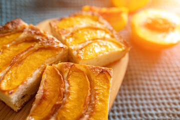 A dessert made of sliced peaches is on a wooden cutting board. The dessert is covered in sugar and looks delicious.