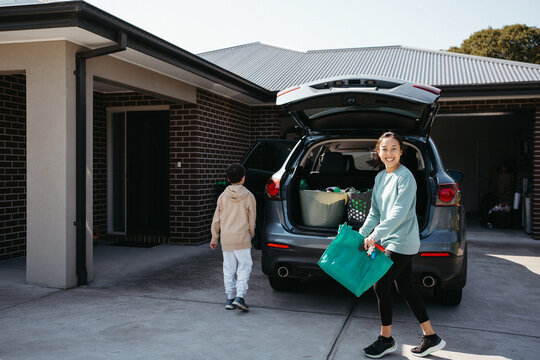 happy woman carrying a reusable shopping bag from the car boot