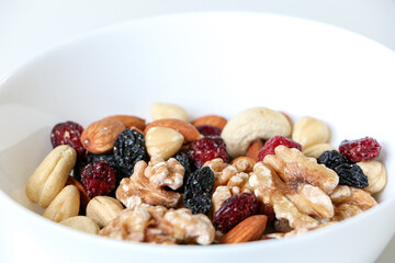 Close up of mixed nuts and dried fruits consisting of almonds, walnuts, hazelnuts, cashew nuts, raisins and cranberries with copy space above, healthy diet, eating and living concept.