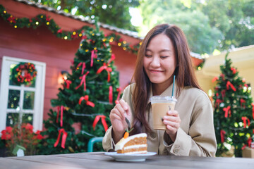 Portrait image of a woman eating a piece of carrot cake and drinking iced coffee in Christmas party