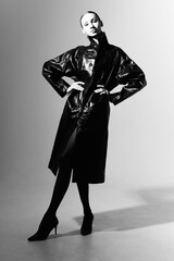 Black and white fashion portrait of female model in black patent leather raincoat.