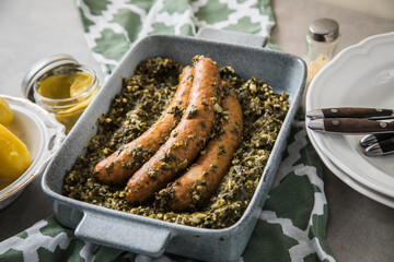 Oldenburger Grünkohl mit Pinkel Kohlwurst in Schale, Salzkartoffeln und Senf auf gedeckten grau...