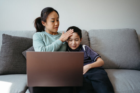 Mum working on her laptop on the couch with her kids.