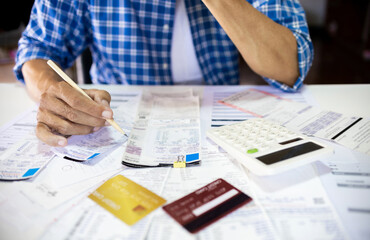 Asian man sitting at desk checking receipt of expenses and all loan bills worry about find money to...