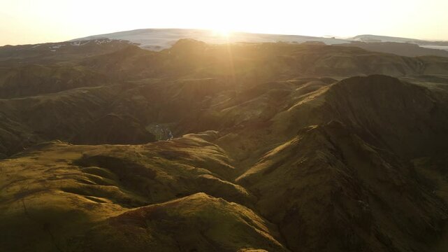 A captivating aerial view of Thakgil, Iceland, as the sunrise bathes the rolling volcanic highlands and valleys in golden light.