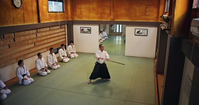 Sensei, students and stick for martial arts, aikido and training with fitness, people and battle in Japan. Teaching, bokken and master for karate, fight and self defense class with exercise in dojo