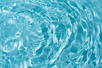 Blue water with ripples on the surface. Defocus blurred transparent blue colored clear calm water surface texture with splashes and bubbles. Water waves with shining pattern texture background.