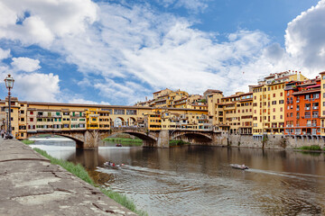 Obraz premium Arno River. Iconic Ponte Vecchio Bridge framed by colorful buildings and a beautiful sky in Florence.