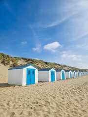 Colorful beach huts lined along a sandy coastline under a bright blue sky Texel Netherlands